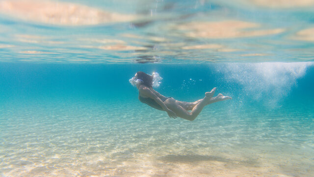 Woman in a swimsuit diving in the blue sea
