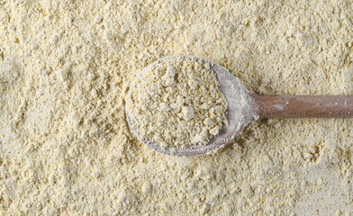 Chickpea flour pile with wooden spoon background and texture