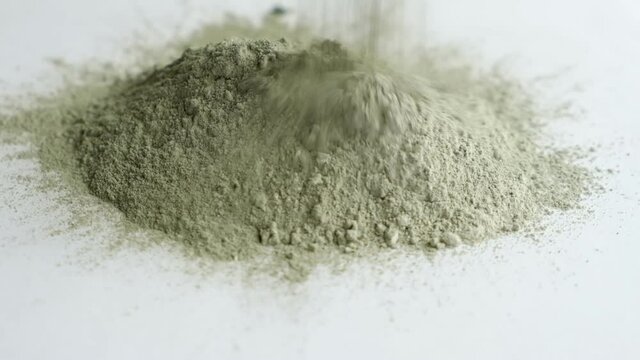 close up green clay powder rotates on white background