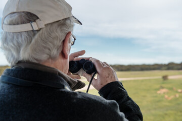 on safari, a man uses binoculars to spot game