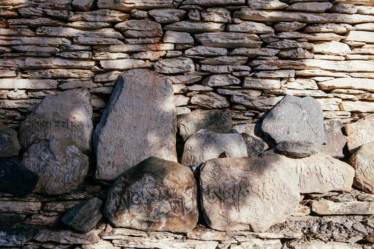 Stones with details of ancient buddhist manuscript near a monastery, Nepal.