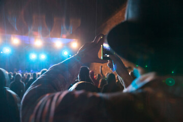 Music fan taking photos with his phone on open air music concert in summertime