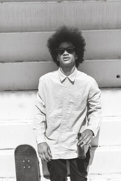 Portrait of an afro black skater man drinking cold beer. Black and white photo.