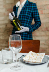 Vertical image.Waiter holding bottle of white wine against break wall, served table