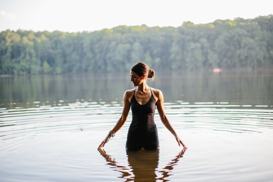 Beautiful woman practicing yoga by a lake
