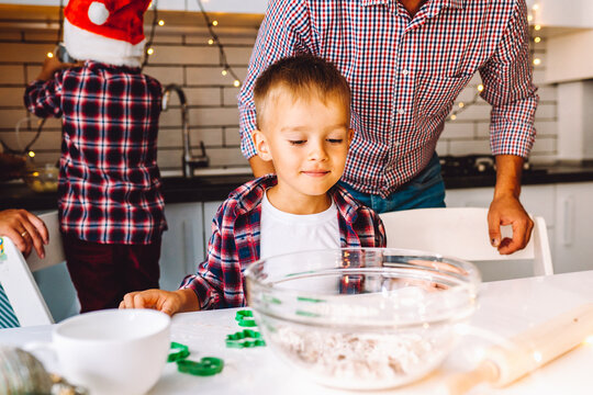 Happy family of father and two children twins sons bake cookies in kitchen before Christmas
