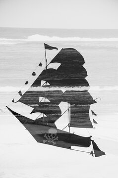 Black and white pirate ship against the sea and crushing waves. Double exposure
