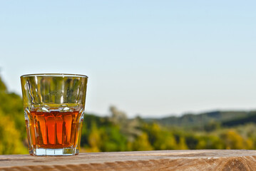 Glass with drink on a background of greenery and nature. Whiskey on an old wooden board. Sunny...