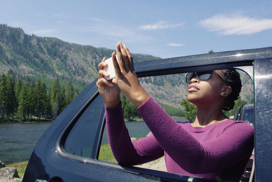 Black young woman taking photos in Yellowstone from car