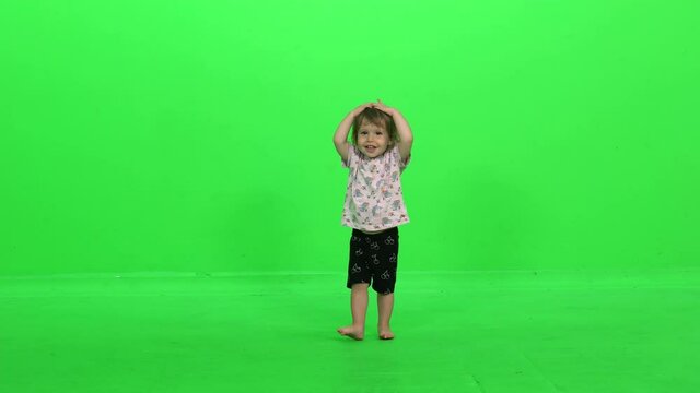 Adorable toddler girl showing her head, her belly, and waving her hands like a butterfly, over green screen.