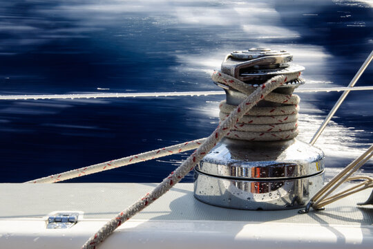 Sailing winch with line on leeward side of sailboat with blue water motion blur