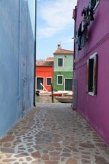 Fototapeta na wymiar Burano island near Venice in Italy, view through colorful houses towards a canal, copy space