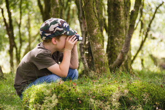 Little boy exploring the woods with his binoculars