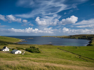 The bay of Otterswick on the east coast of the island of Yell in Shetland, UK, taken on a calm, sunny day with light cloud in summer.