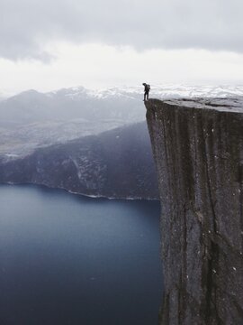 A distant hiker standing on a cliff with his shoe outside the edge