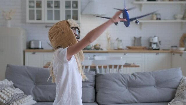 Slow motion girl imagines herself as an aircraft pilot child's desire fly high in sky. Cute blonde caucasian girl in glasses and cap an airliner captain, playing with toy passenger plane. Travel fly
