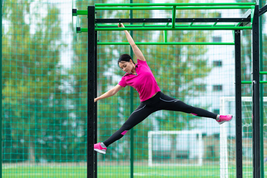 Fit sporty young woman working out on parallel bar