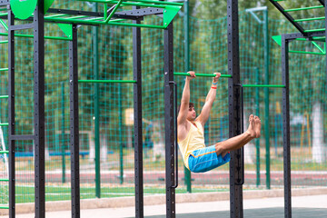 Muscular barefoot athlete working out on bars