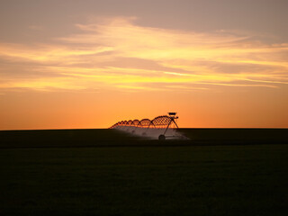 Center pivot irrigation system in the farm field at sunset