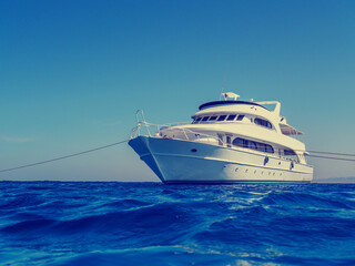 Fototapeta na wymiar White yacht in the blue sea, retro instagram style filtered