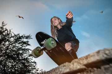 Teen girl riding a skateboard. Beautiful young skater riding on her longboard in the city © andyborodaty
