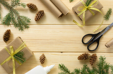Christmas flat lay of gift boxes with wrapping paper, scissors and decorations on wooden background. Space for text