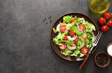Vegetable salad with tomatoes, red onions and sauce on a black background.