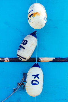 Vertical photo of a blue boat hull with a string of white buoys with painted numbers and ""XO""