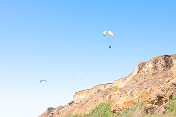 Fototapeta na wymiar Paraglider in the blue sky. The sportsman flying on a paraglider.