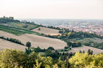 Fototapeta na wymiar Panoramic view of Bologna from Bolognese hills. The city in background with rural fields and wheat in close up. Emilia Romagna Region, Italy