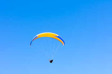 Paraglider in the blue sky. The sportsman flying on a paraglider.