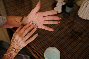 hand detail of a 90 year old woman hydrating his hands indoors