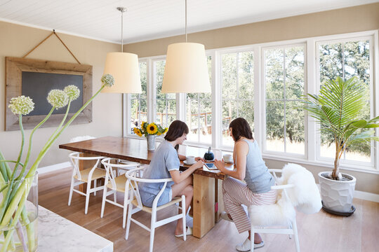 Girlfriends looking at tablet at dining room table of modern farmhouse