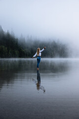 Fototapeta na wymiar woman raised his hands up. he stands in a mountain foggy lake. Premium Photo 