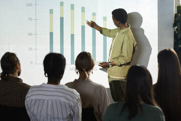 Portrait of young African-American man pointing at data graph while giving speech or report on...