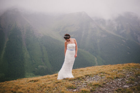 Bride standing on top of a mountain ledge in her wedding dress