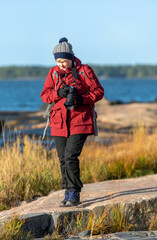 Woman photographer taking pictures with SLR camera at seashore in autumn