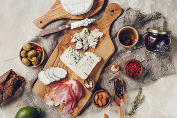 Set of cheese, hamon, honey, green olives, nuts and spices on rustic wooden board