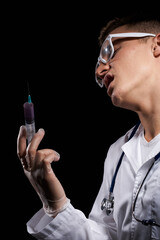 Doctor with liquid in a syringe on a black background and a stethoscope around his neck cropped view