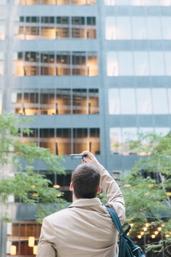 Young Professional Man Taking Photo with Smartphone Camera Technology in New York's Wall Street Business District