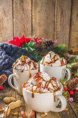 Salted Peanut Caramel Hot Chocolate. Keto and vegan hot chocolate recipe, with marshmallow and whipped coconut cream, wooden background with christmas winted decoration