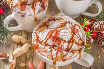 Salted Peanut Caramel Hot Chocolate. Keto and vegan hot chocolate recipe, with marshmallow and whipped coconut cream, wooden background with christmas winted decoration