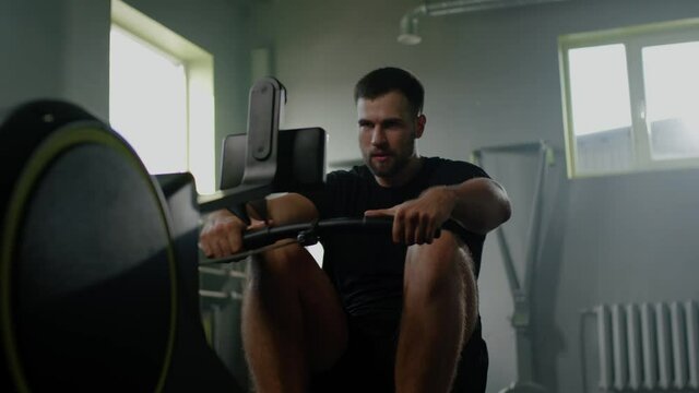 Sportsman Do Hard Exercises With Rowing Machine .