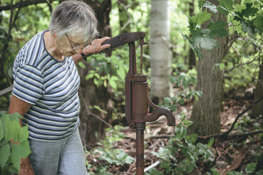 Senior Woman Fetching Water from an artesian Well at Backwoods of her Tree Farm