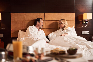 Cheerful couple relaxing in bed of the hotel room