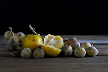 Oranges and Longkong (Thai fruit) rotten and withered fruits with fungus and fruit fly on old...