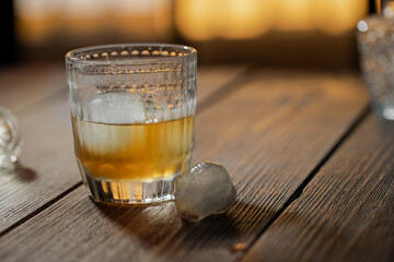 Whisky, bourbon or cognac in glass with ice ball and  crystal bung on wooden table. Alcohol drink background