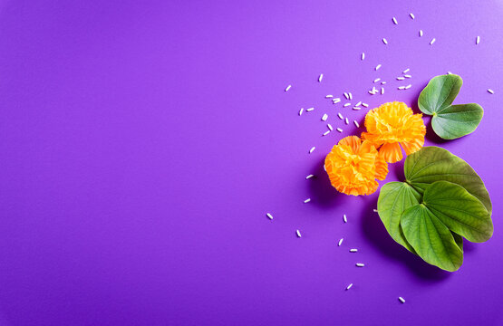 Happy Dussehra. Yellow flowers, green leaf and rice on purple pastel background. Dussehra Indian Festival concept.