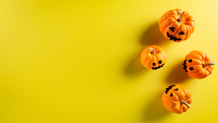 Halloween decorations made from ghost pumpkin on pastel yellow background. Flat lay, top view with copy space for text.