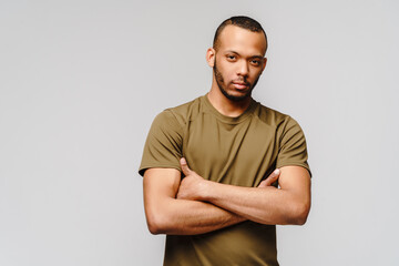 Joyful friendly african-american young man in green t-shirt over light grey background with copy space